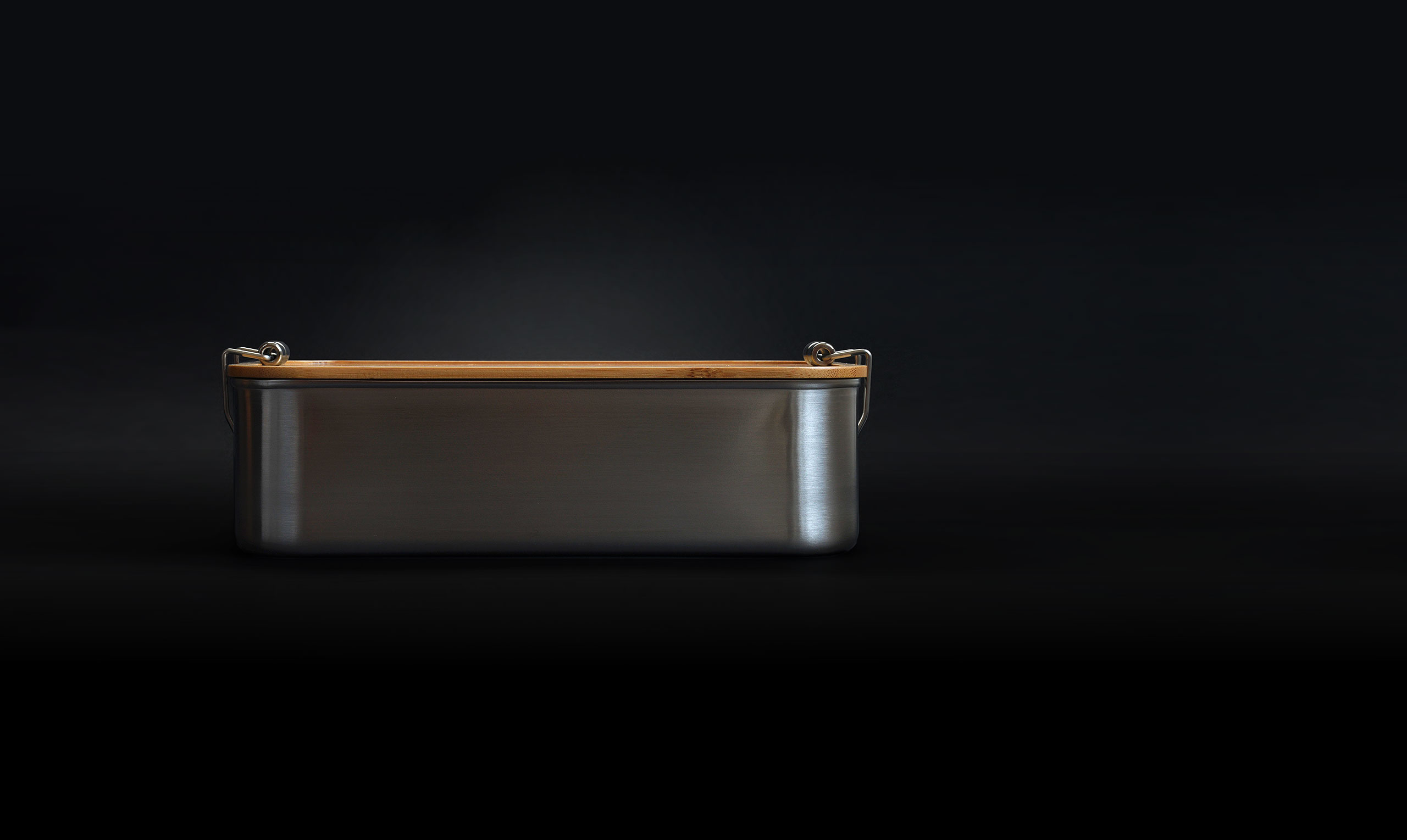 Lunchbox aus Edelstahl mit Bambusdeckel und Clip-Verschlüssen. Seitenansicht vor dunklem Hintergrund.